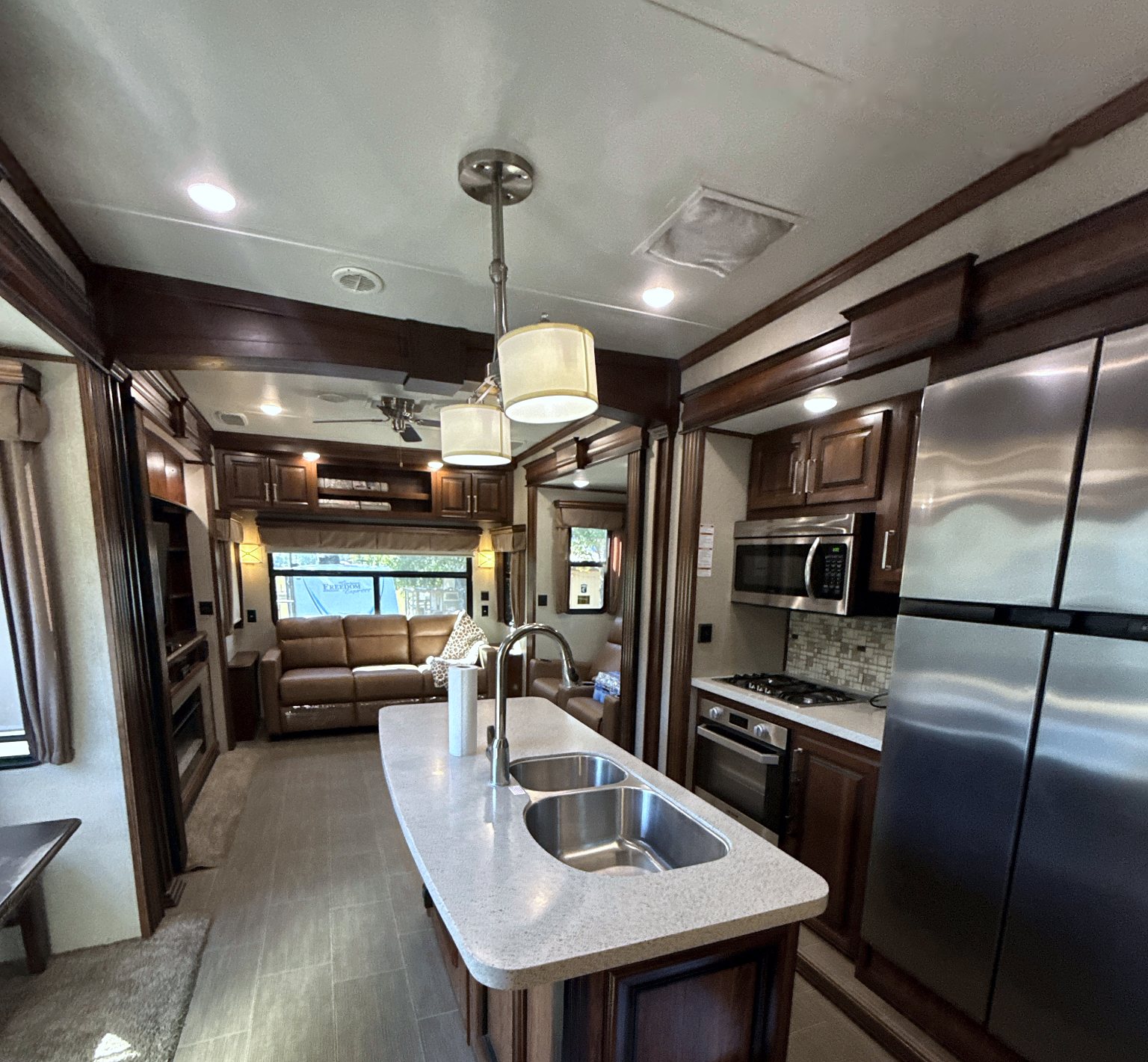 Camper kitchen island with a double sink across from the range and refrigerator