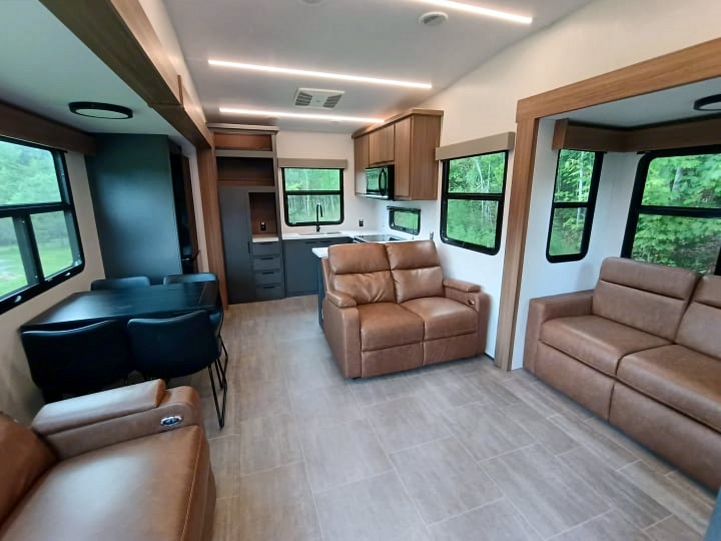 Camper living area with reclining seats, a sofa, and a dining table