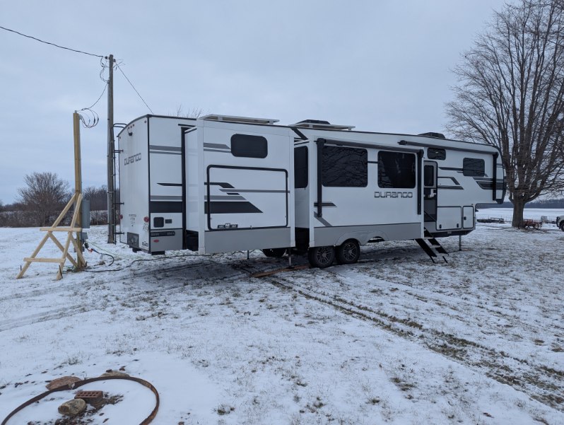 Temporary RV housing set up in snow on a homeowner's property during winter repairs by Agile RV Housing