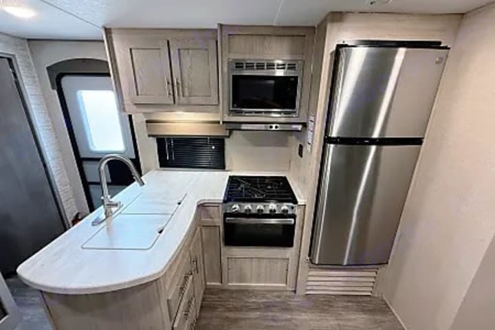 Camper kitchen with gas range, microwave and stainless refrigerator