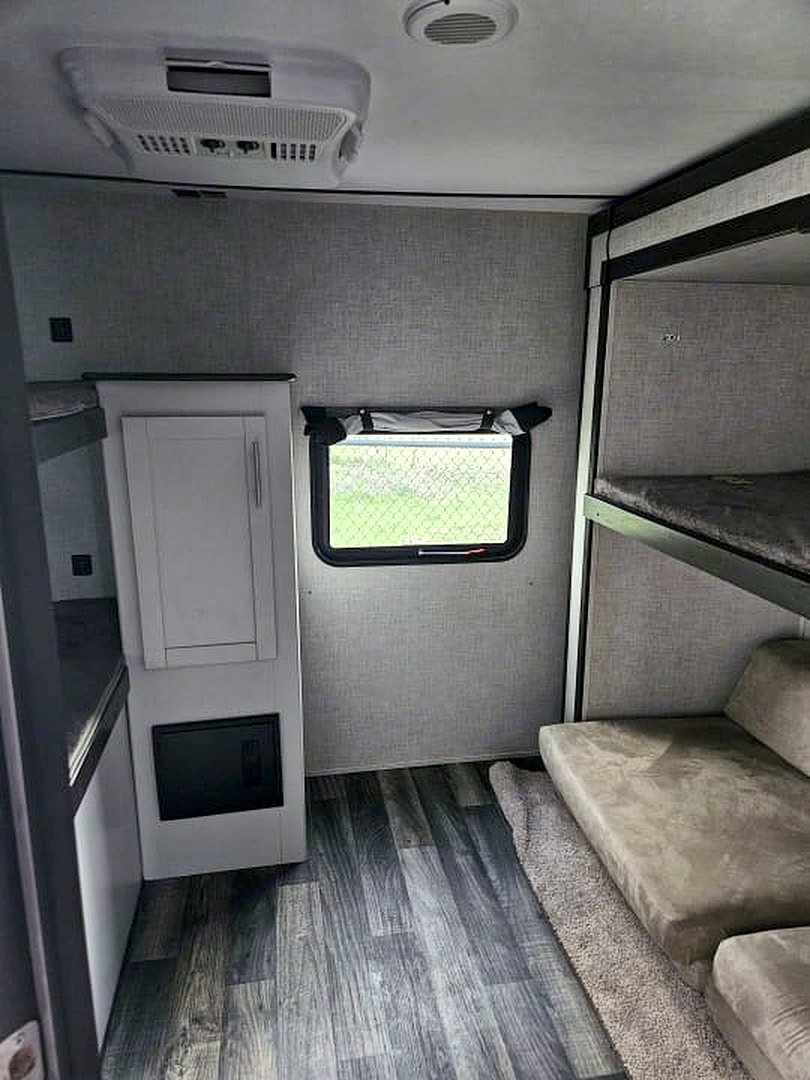 Camper bunk room with a cabinet, a window, and bunks