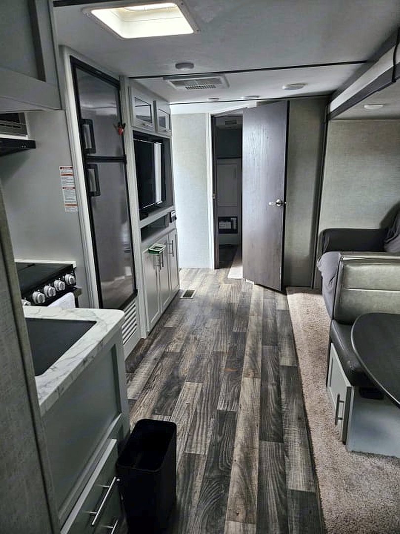 Camper interior looking past the kitchen toward a door at the far end