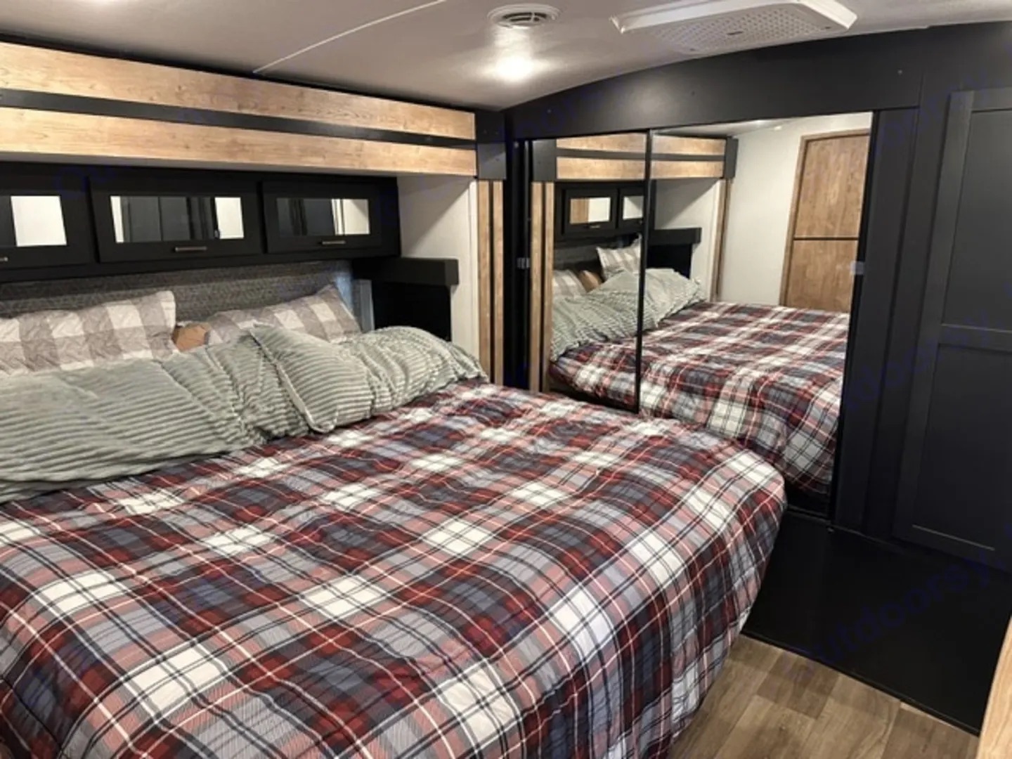 Camper main bedroom with a king bed and mirrored wardrobe