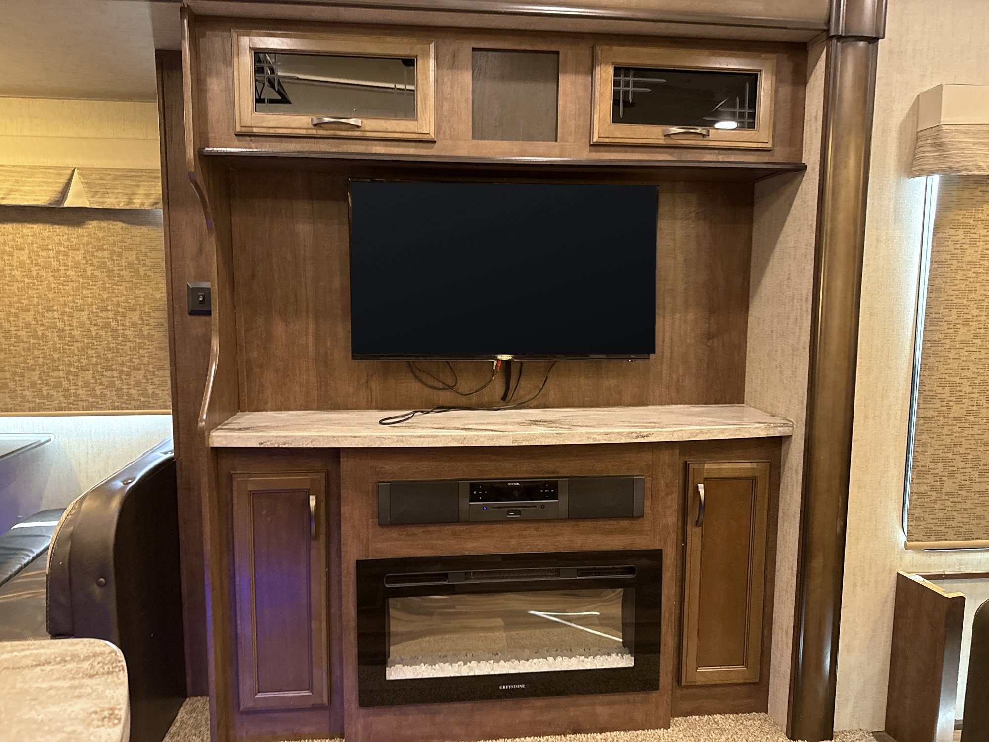 Camper entertainment center with a television above an electric fireplace