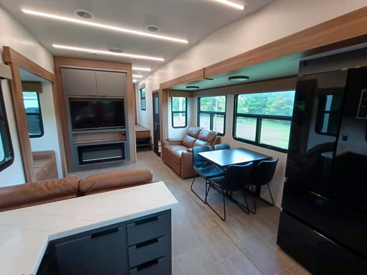 Camper kitchen island looking toward the dining table and an electric fireplace