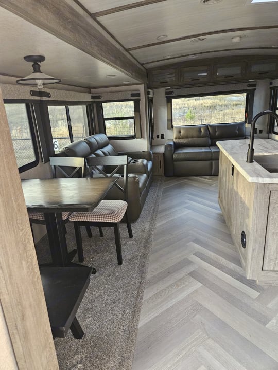 Camper dining table, theater seating and a sofa along the rear windows