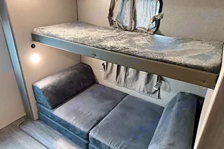 Camper bunk room with upper bunk and cushioned lower berth