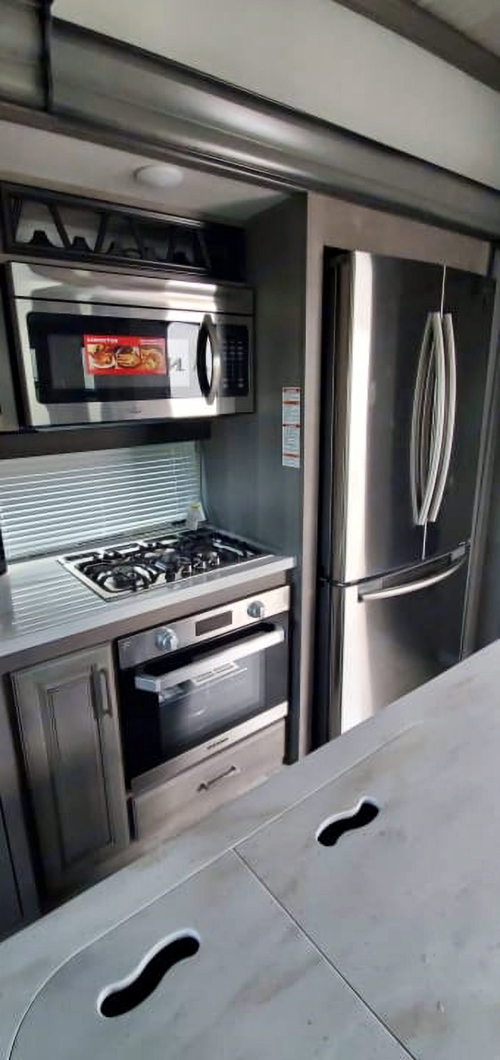 Camper kitchen with a gas range, oven, microwave, and stainless refrigerator