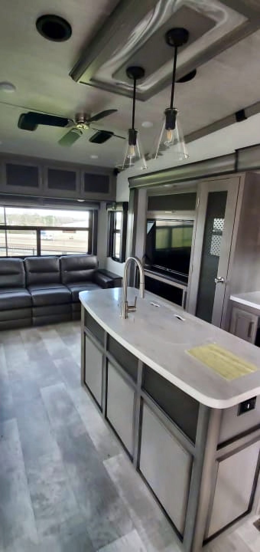 Camper kitchen island with pendant lights and a reclining sofa beyond it