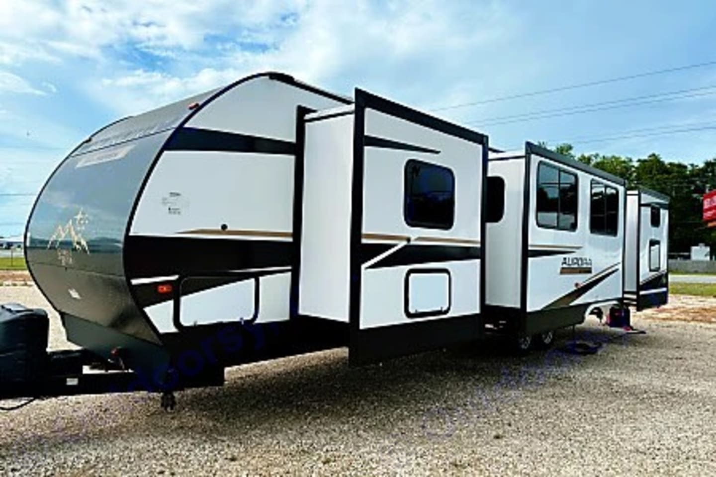 Exterior of a Forest River Aurora bunkhouse travel trailer with slide outs extended