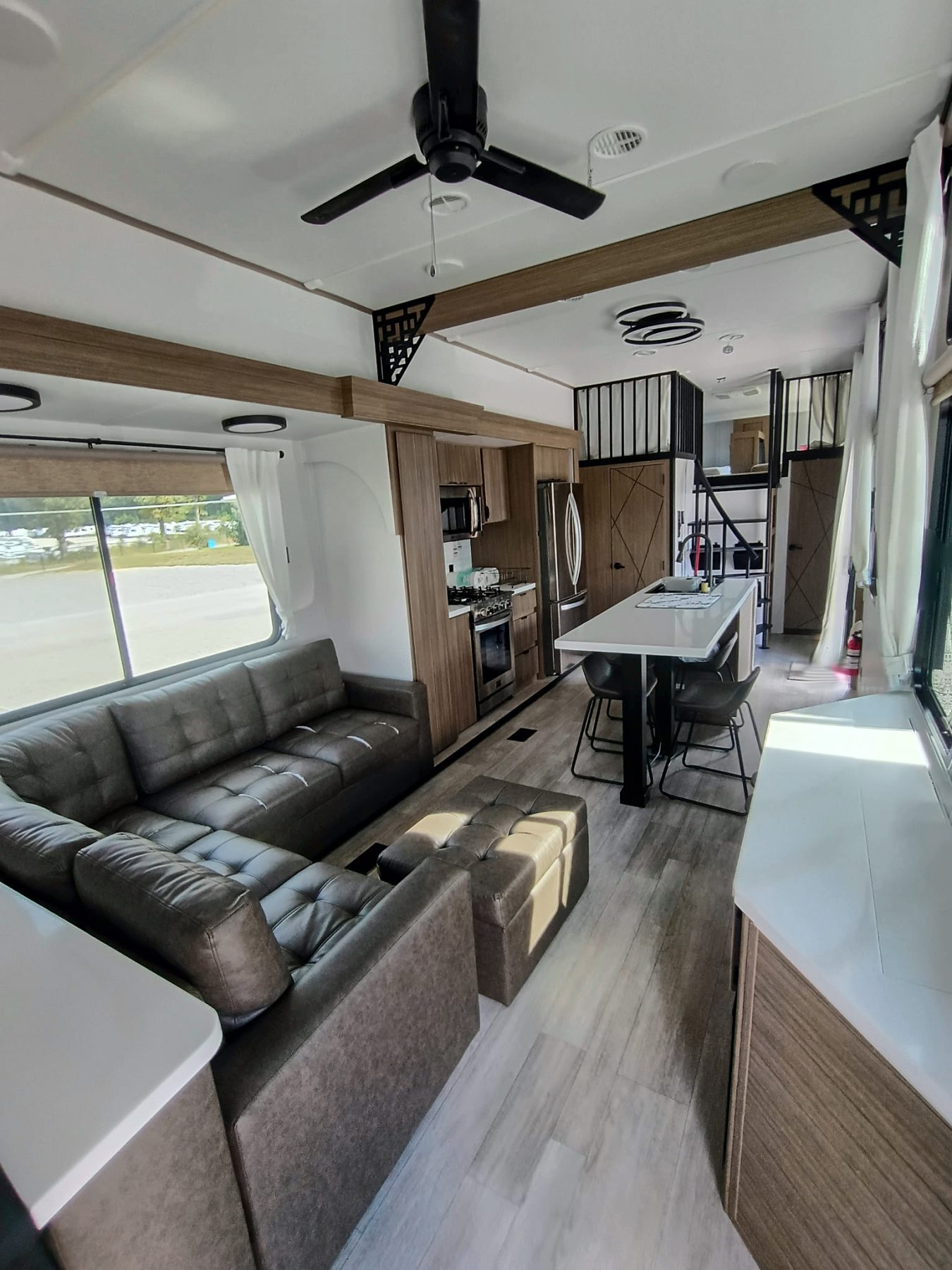Camper living area with a sectional sofa looking toward the kitchen island