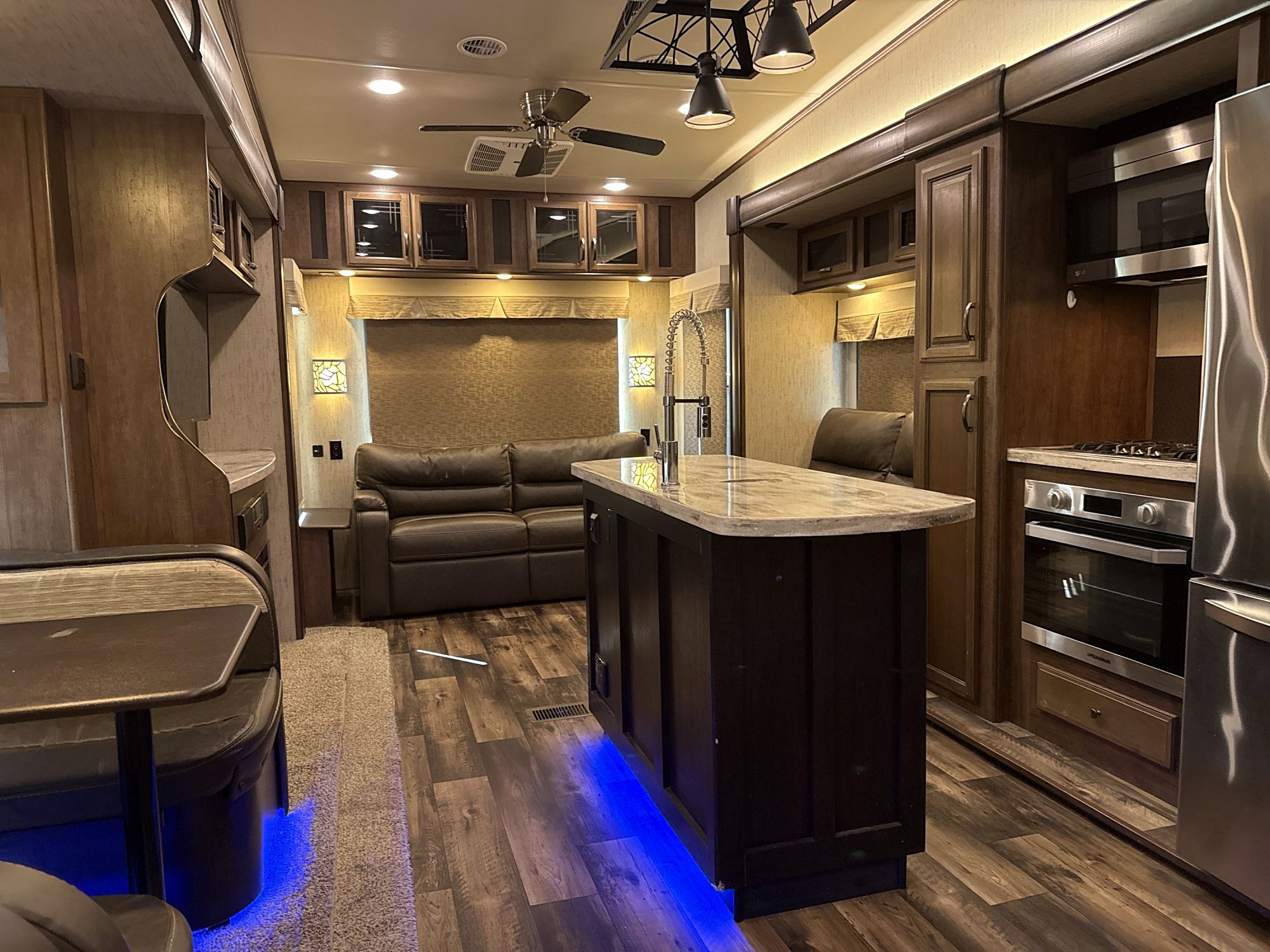 Camper kitchen island with a sink, looking toward a sofa in the rear living area