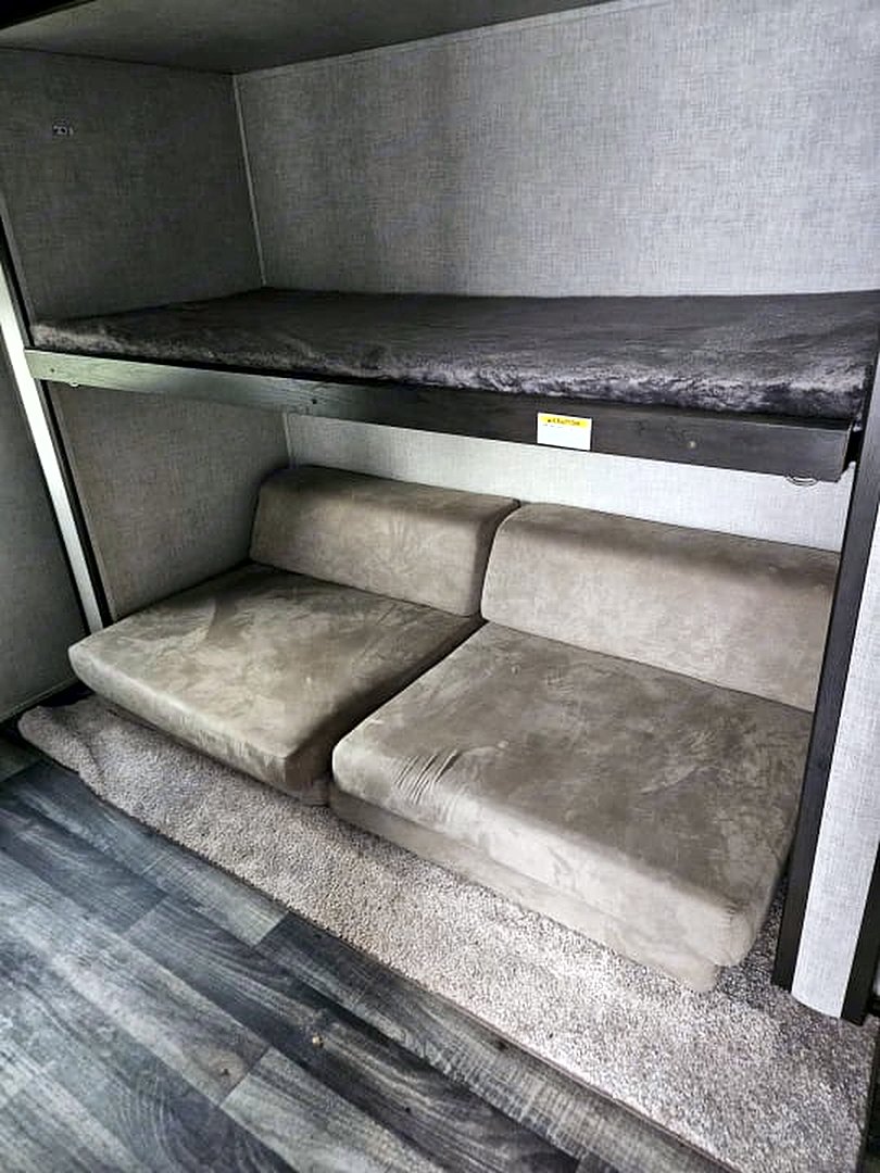 Camper upper bunk above a cushioned lower bench