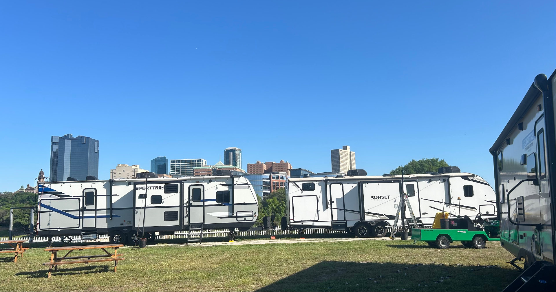 Multiple RV units deployed on a grassy workforce site with a city skyline in the background.