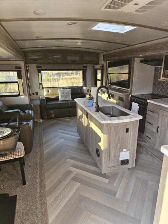 Camper interior looking past the kitchen island toward the rear living area
