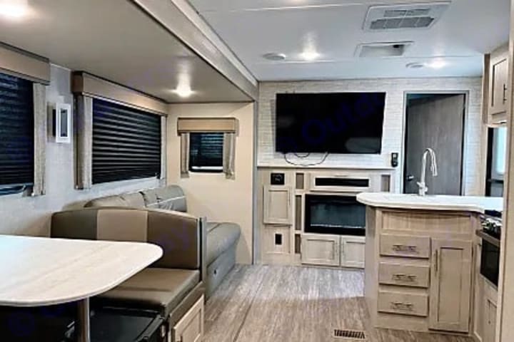 Camper living area with sofa, dinette, television and fireplace