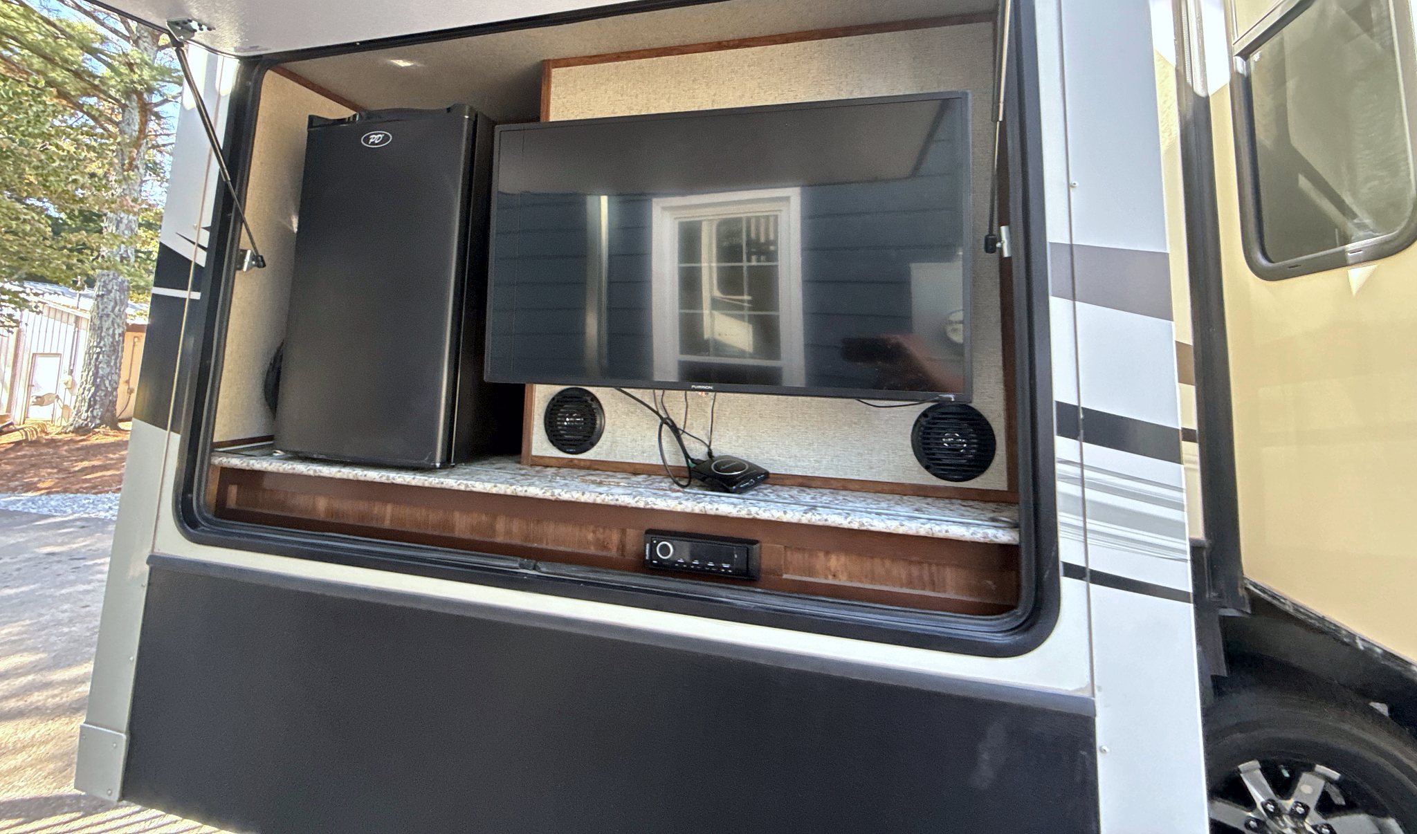 Outdoor entertainment compartment on the fifth wheel with a television and a mini fridge