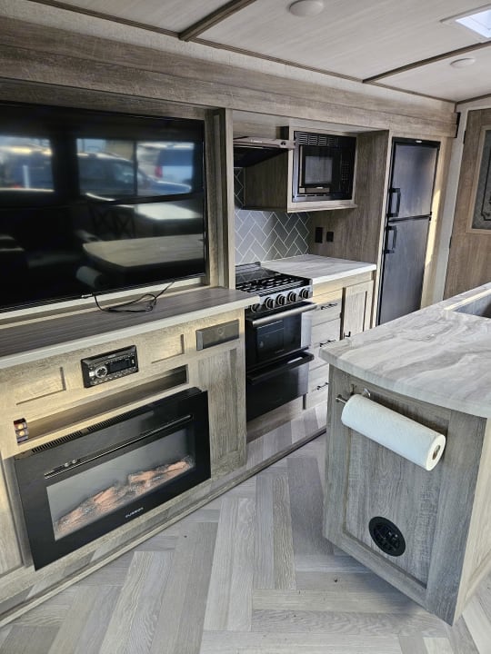 Camper entertainment center with a large television above an electric fireplace