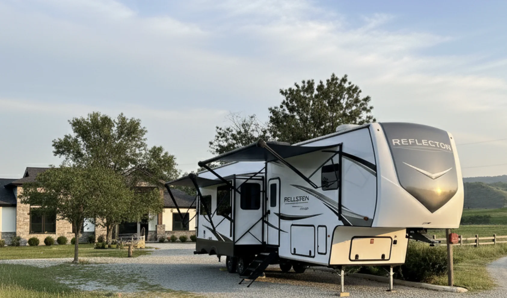 Fifth-wheel camper set up on the driveway of a residential property.